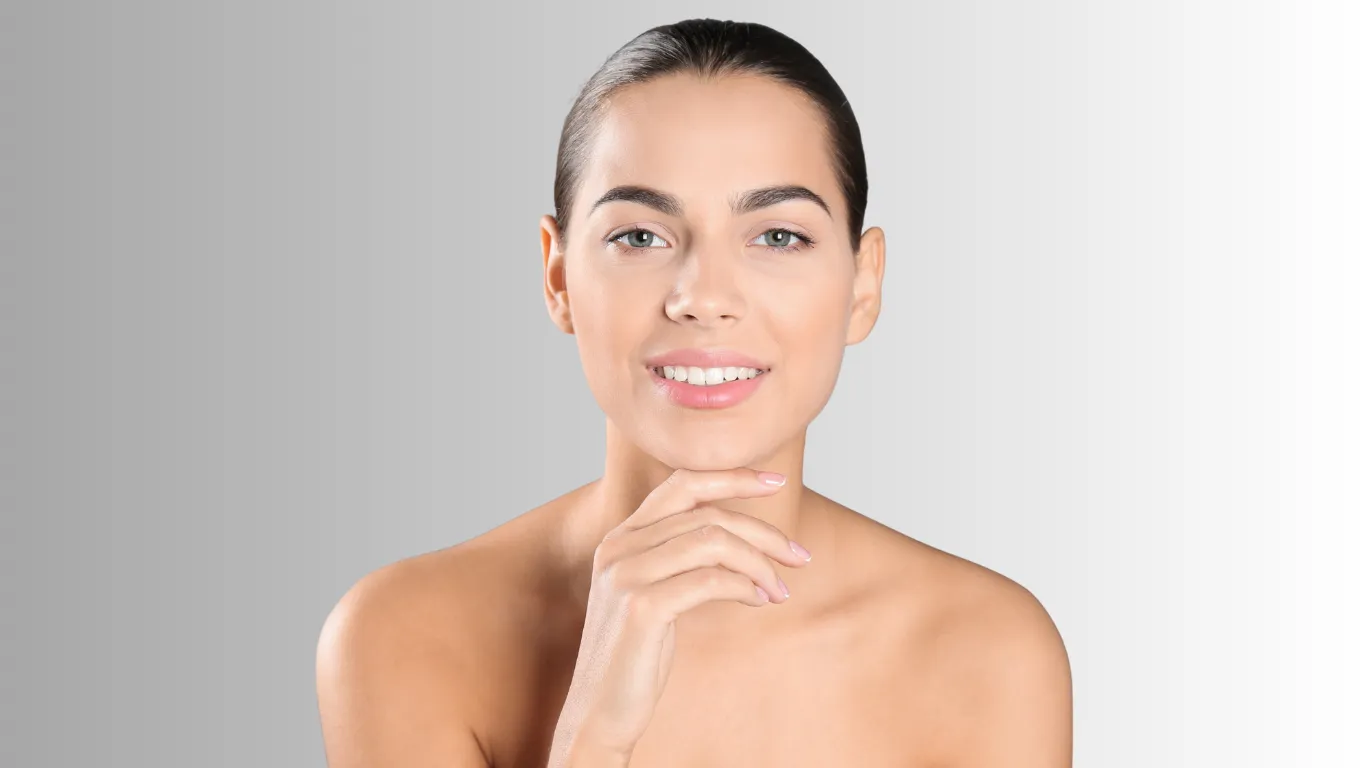 Smiling woman with hand near chin, photographed against a gray background